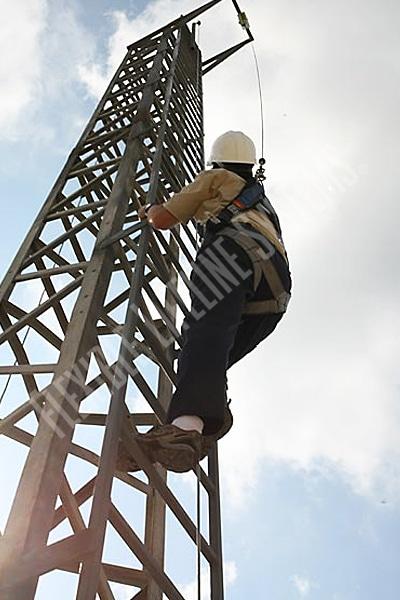 worker climbing vertical tower wearing fall protection